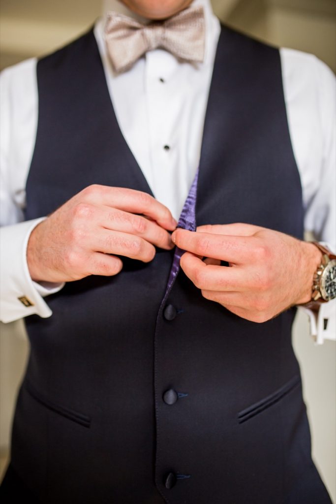 The groom takes great care when buttoning up his vest on his big day at La Cantera Resort & Spa.