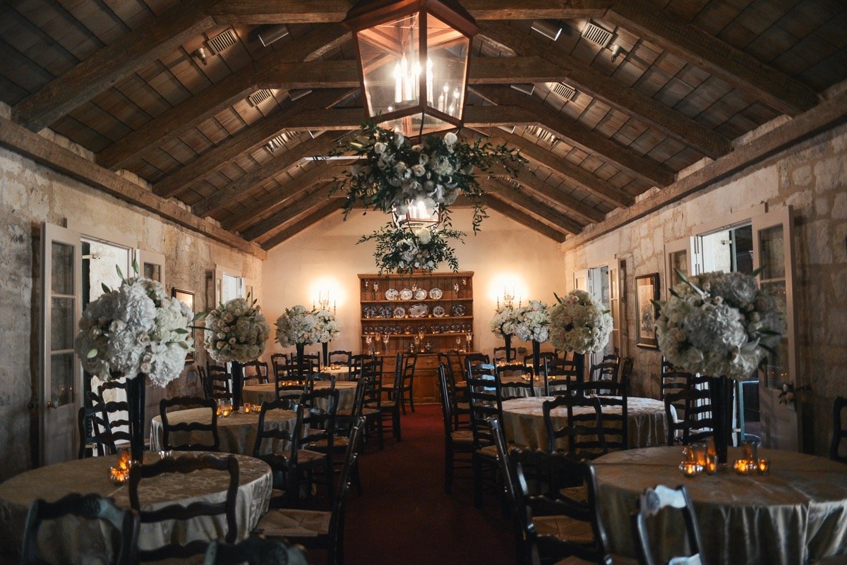 Alamo Plants & Petals shows us a room of tables and chairs with long-stemmed balls of white roses.