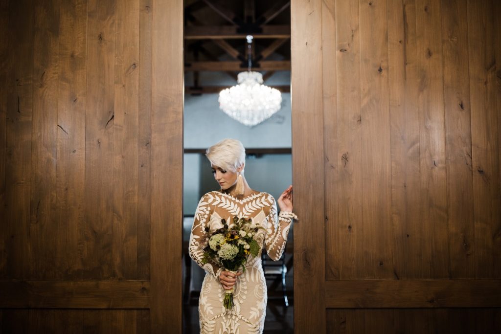 A woman stands in the doorway holding a bouquet. she is very pretty. The Chandelier of Gruene