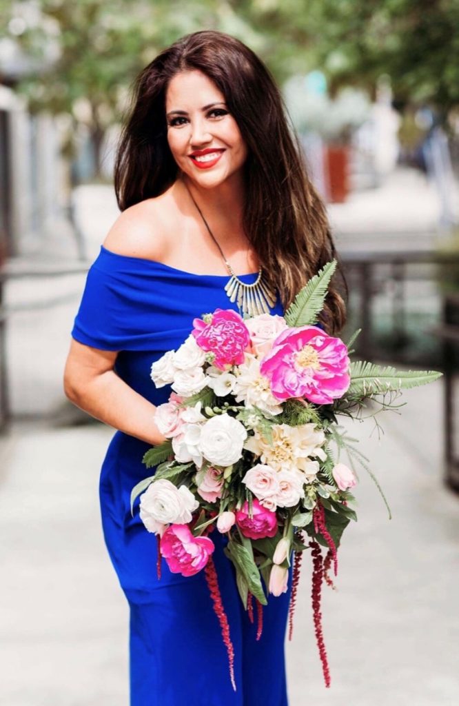 A pretty woman in blue with a Freesia Designs bouquet of flowers.