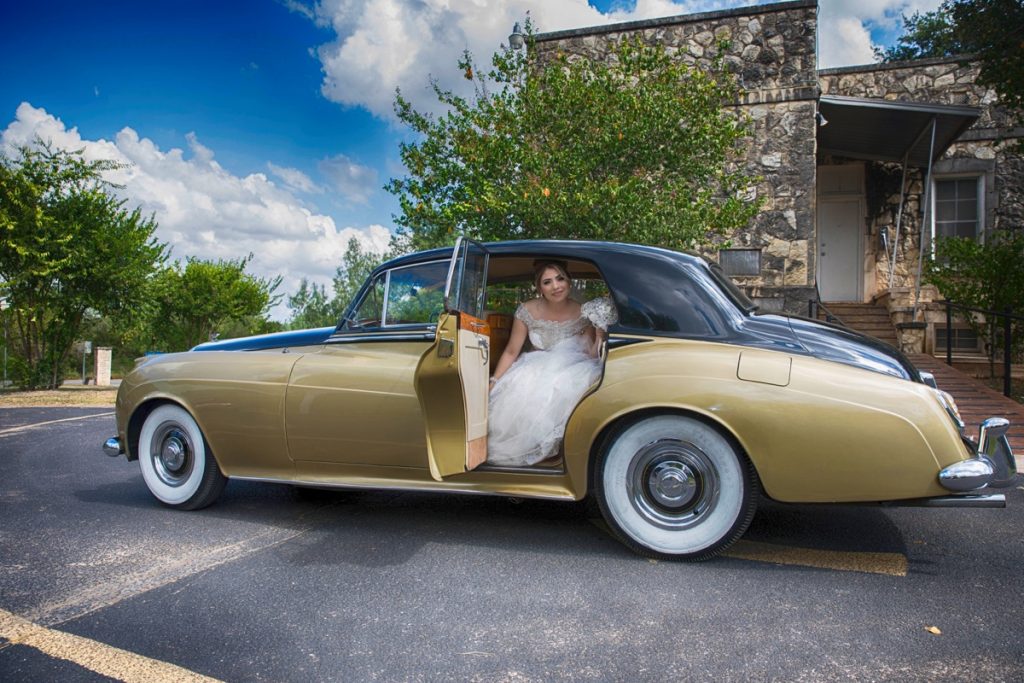 A beautiful bride emerges from a Rolls Royce in the parking lot of The Emporium by Yarlen.