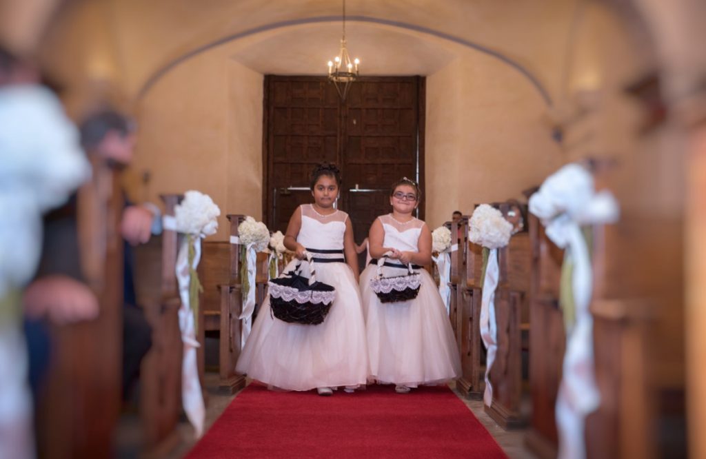 Two flower-girls are throwing petals down the aisle that the Bride will soon walk down.