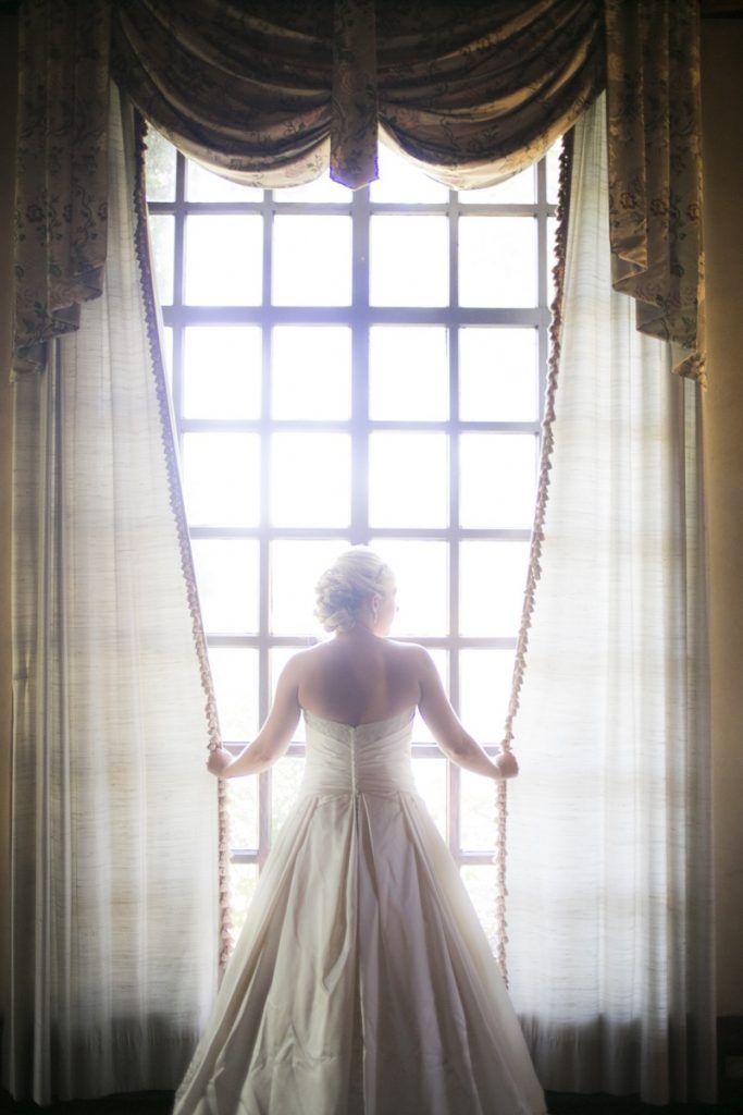 The Bride, by herself, famed by The Dominion long, tall windows.