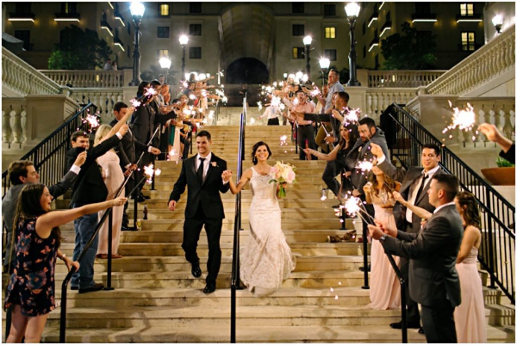 A bride and groom walk down The Eilan Hotel Resort and Spa stairs as guests exhibit sparklers and "Yays"