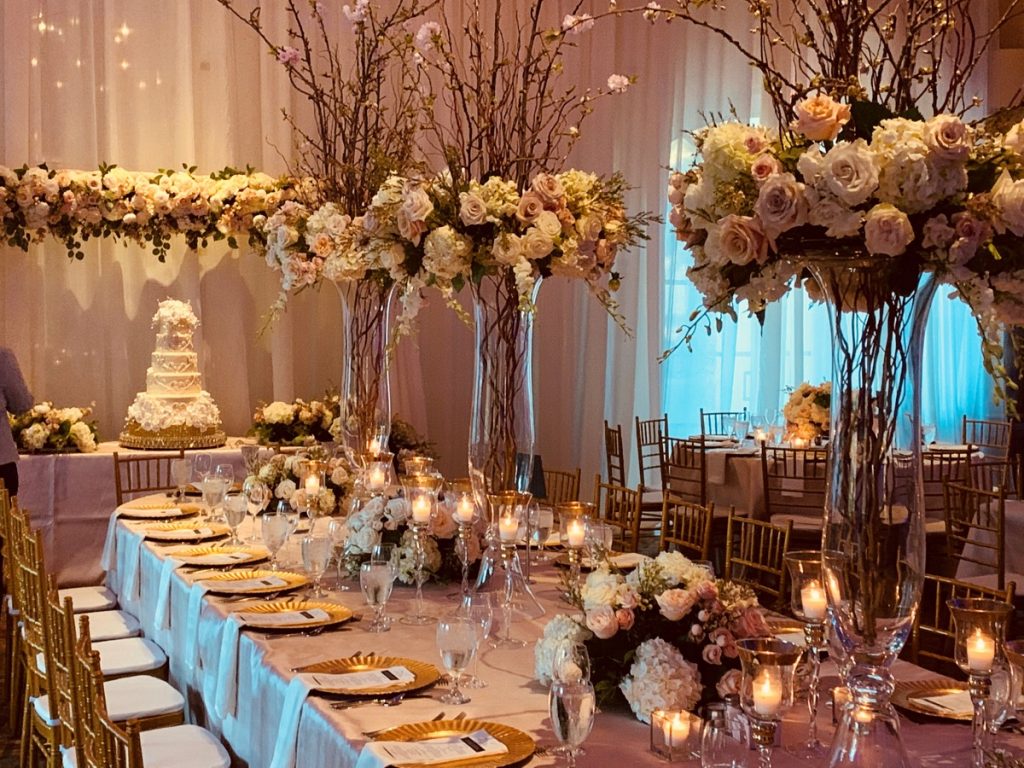 A long Party Table, enhances by flowers and decorations by Events by A Touch of Elegance leads the eye to the Bride's wedding cake. Just lovely!