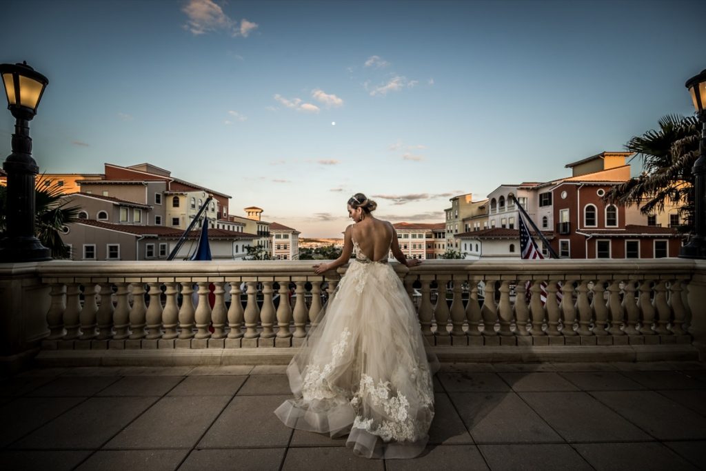 a model bride stands pensively on the balcony overlooking the Tuscan-style buildings at The Eilan Hotel Resort and Spa.