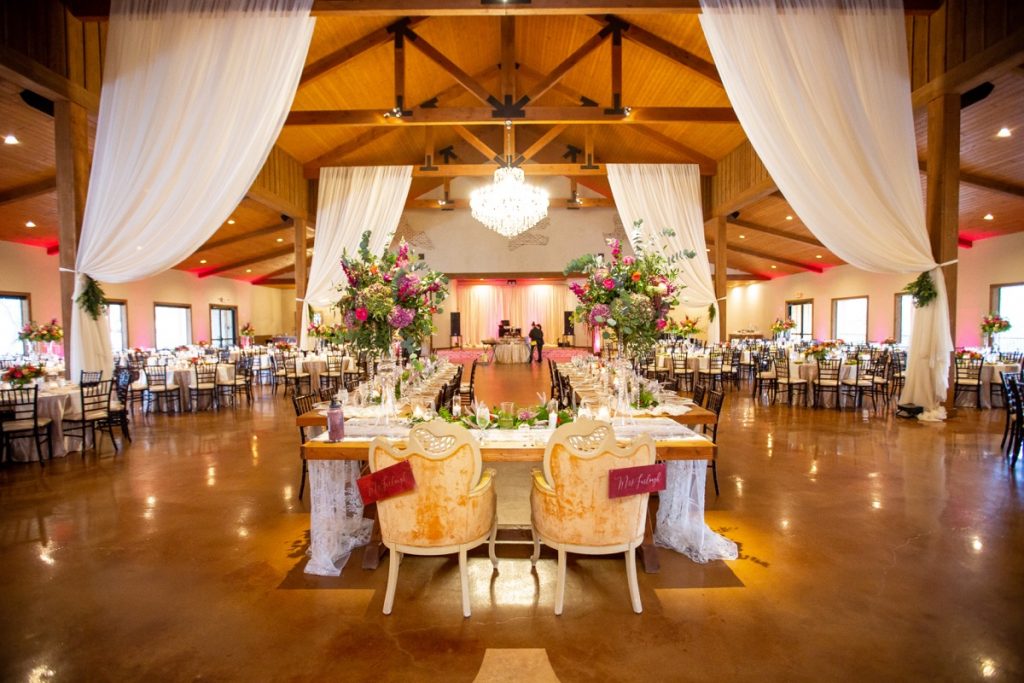 The Chandelier of Gruene banquet room displays a u-shaped table with the groom and bride at the front.