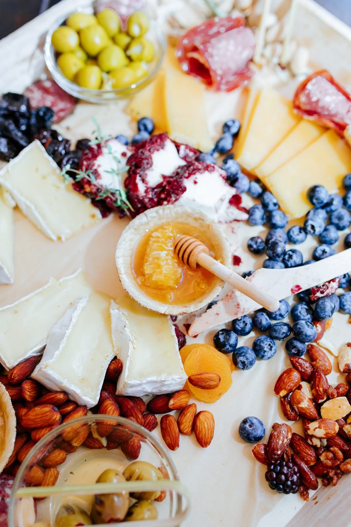 charcuterie board with cheese blueberries honey and almonds