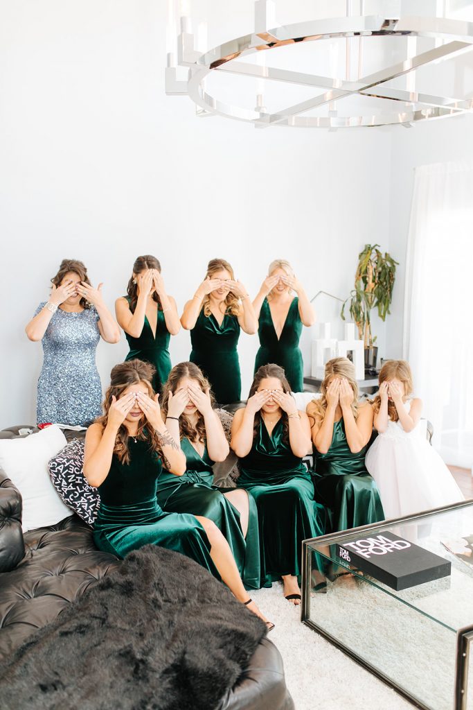 bridesmaids covering their eyes while they wait to see the bride in her wedding dress for the first time