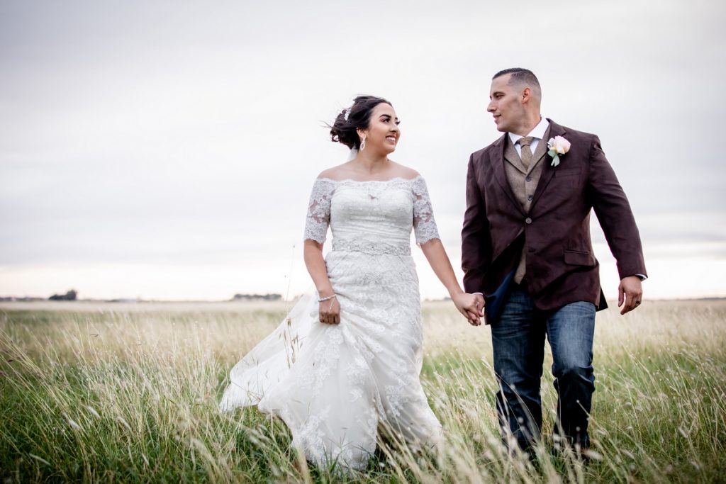 Wedding couple walking through meadow